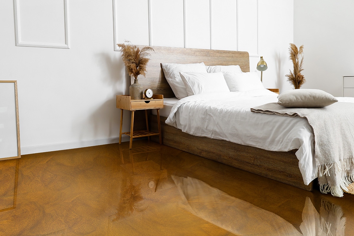 Comfortable bed, wicker rug and nightstand table with dry reeds Comfortable bed, wicker rug and nightstand table with dry reeds near white wall